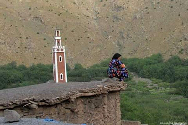 berber village 4 women setting on roof of old house with mosque tower in backgroud
