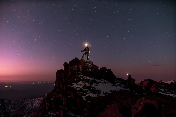 man standing on rock with head lamp