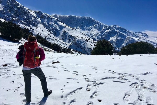 man standing in mountain passe with snow on