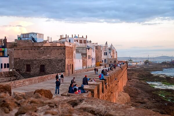 people siting on a wall near the sea